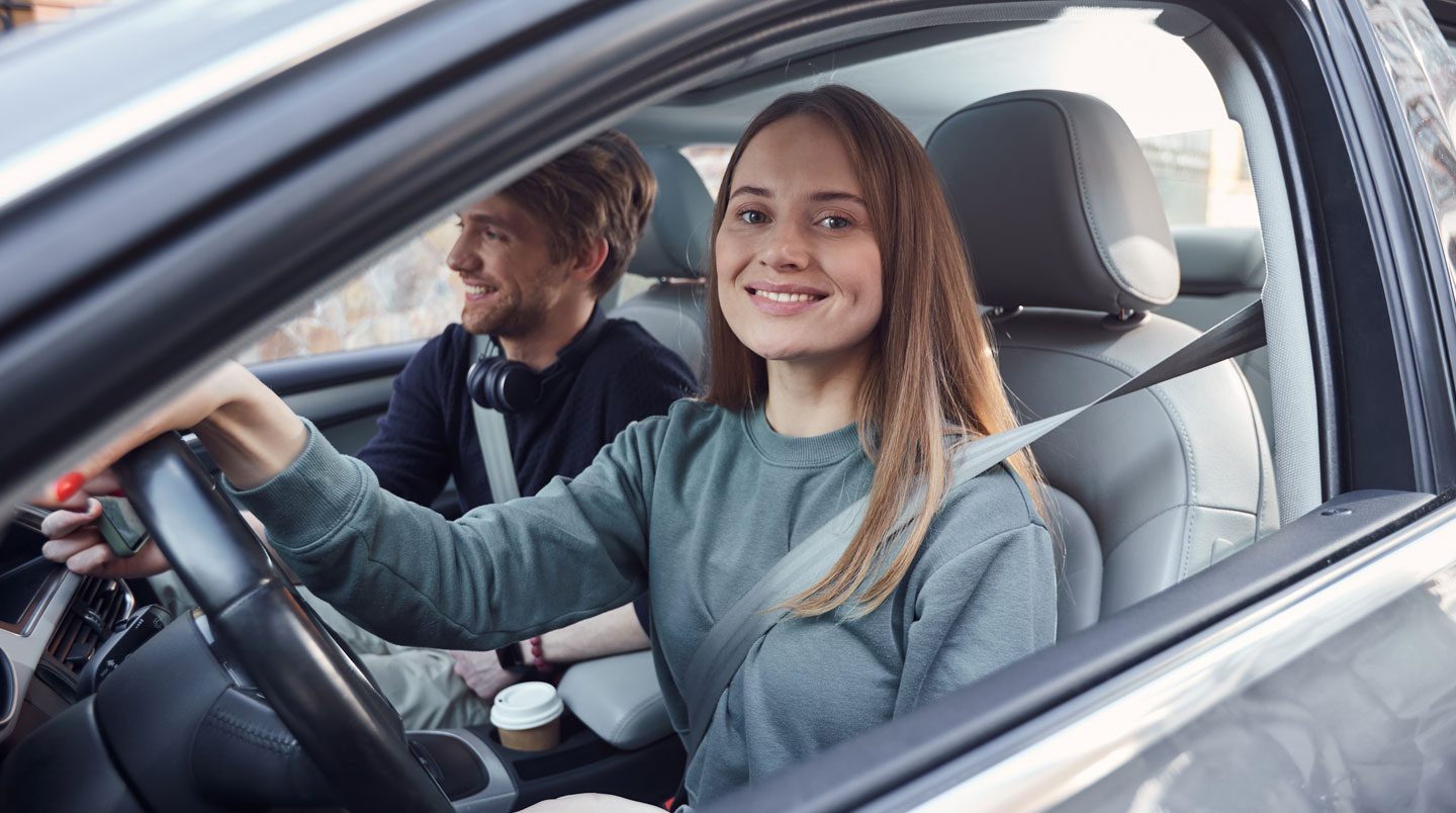 Les mains d'une jeune personne tiennent une carte verte d'assurance et des clés de voiture au-dessus d'une table de cuisine familiale